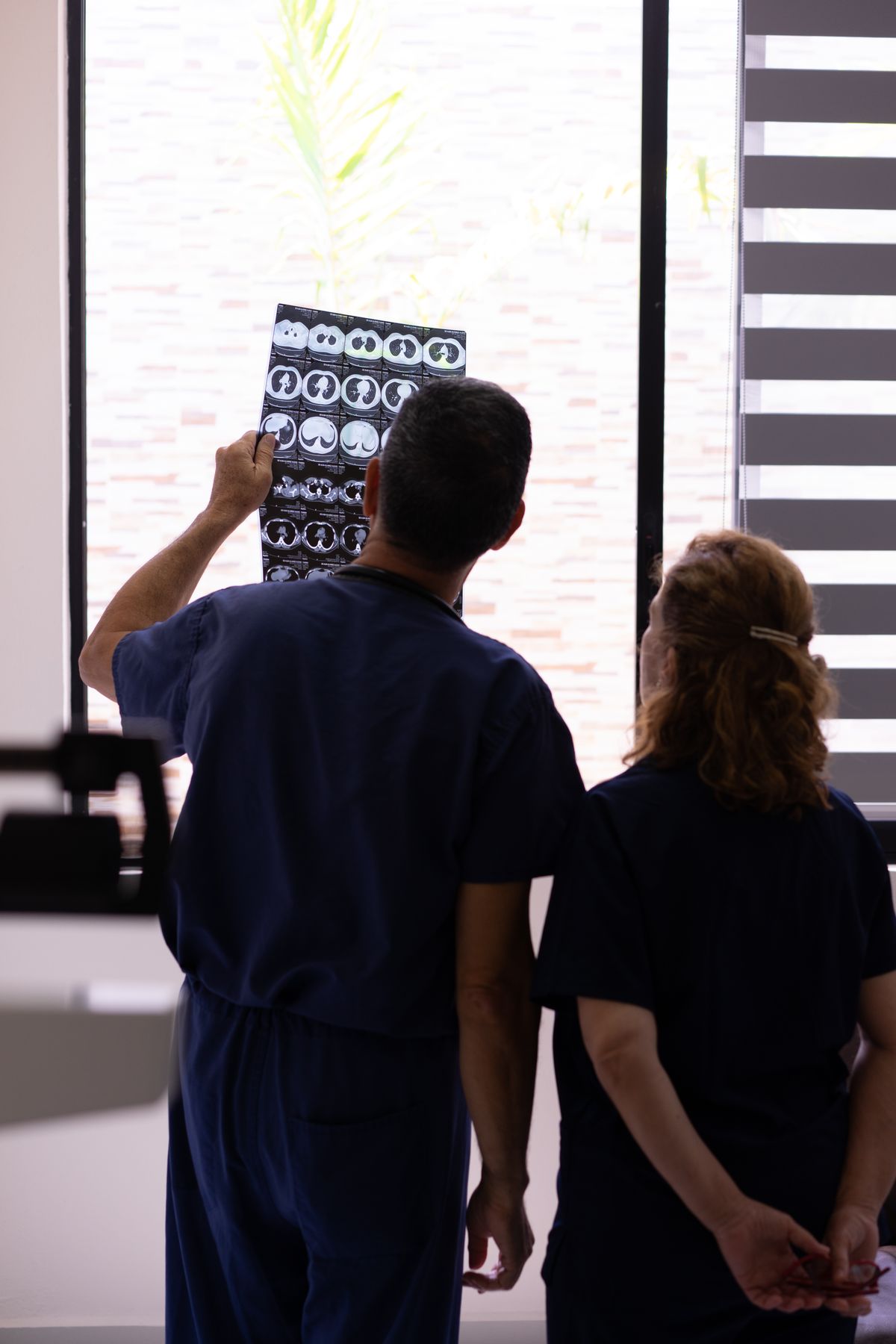 Two clinicians seen from behind reviewing an X-ray on a lightbox