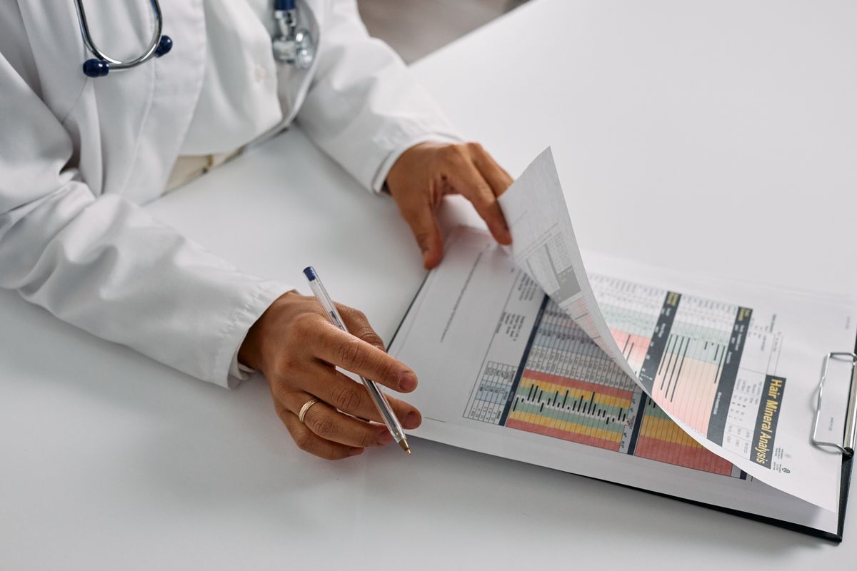 A doctor annotating a printed report on a clipboard