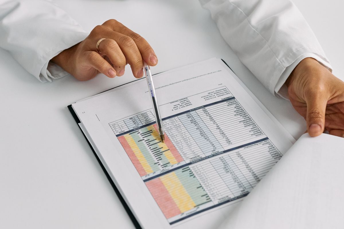 A clinician's hands marking up a printed workflow report